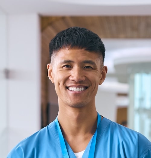 Close-up of an Asian man in medical scrubs, focused and ready for surgery in a healthcare setting.