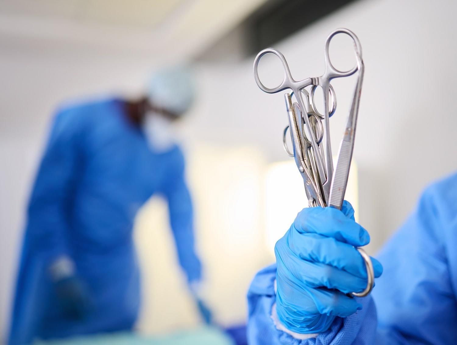 Close-up of surgical scissors in a doctor's hand during an operation in a hospital operating theater, highlighting precision in surgical procedures.